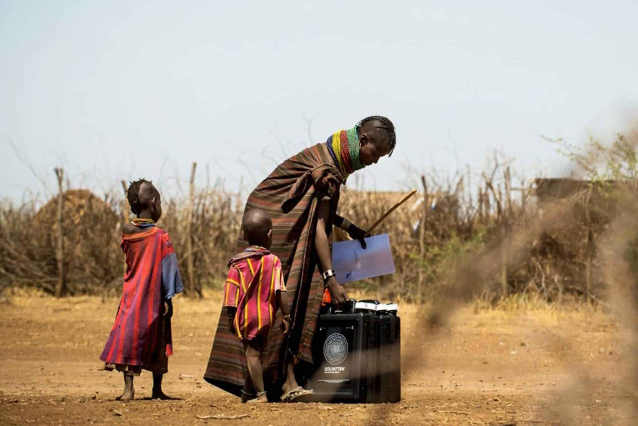 Mamma och två barn går med en vattendunk skänkt av Solvatten